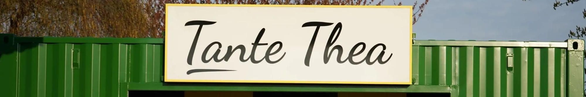 Grüner Automatencontainer von Tante Thea mit großem Schild über dem Eingang